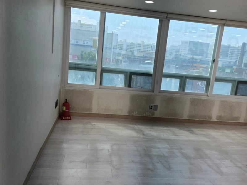 창밖으로 도심 전경이 보이는 교습소 내부, 벽 마감재 철거 후 모습