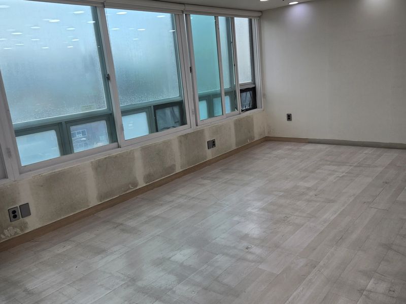 통창 옆 벽면 마감재를 철거 중인 교습소 내부 모서리