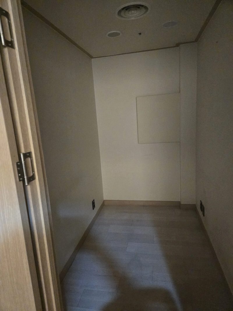 천장 환기구와 매립등, 벽면 패널이 보이는 소형 방 내부 참고사진